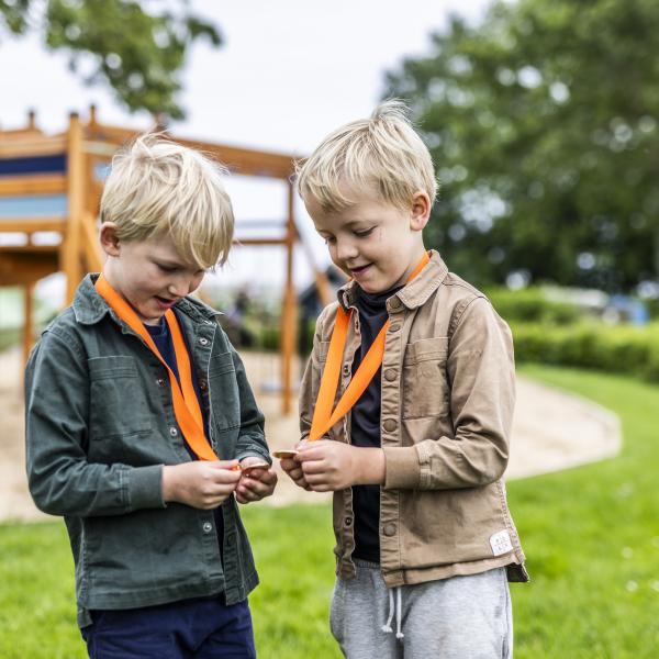 Two boys on a playground with orange medals around their necks